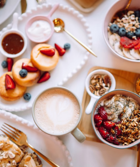 Genussfrühstück im Karol Vienna © unsplash.com / George Dagerotip Frühstückstisch mit Müsli, Kaffee, Porridge & Pancakes